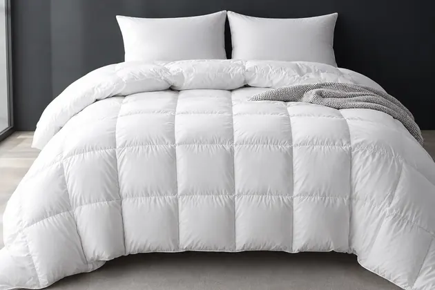 White box-stitched goose feather comforter on a bed with two white pillows
